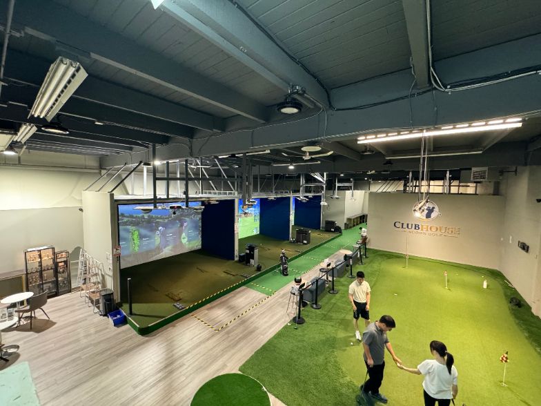 The same floor finished as a multi-bay venue with simulator bays and a putting green