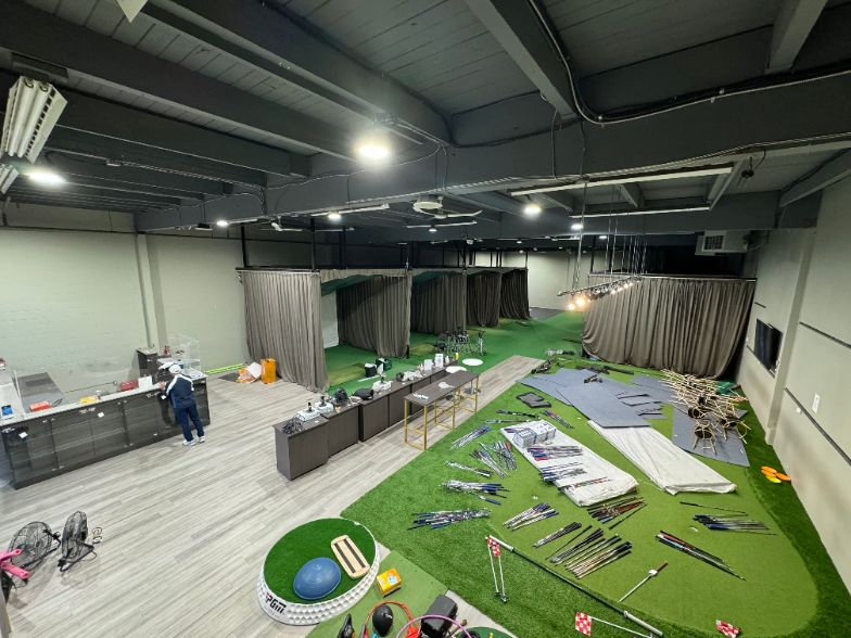 Large commercial floor mid-build with curtains, turf rolls and equipment laid out