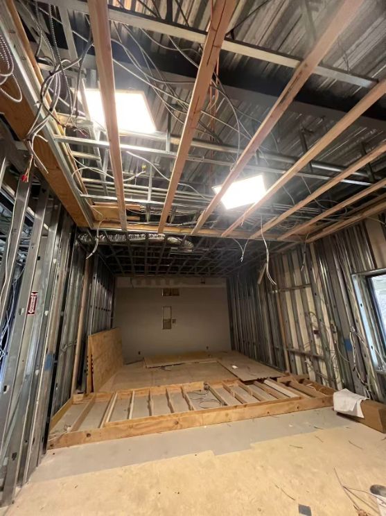 Stripped room with exposed steel studs, open ceiling and a wooden platform frame